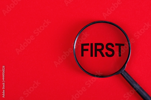 Magnifying glass with the inscription FIRST on a red background.