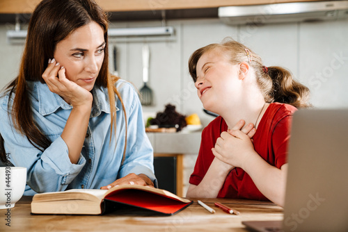 White woman helping her daughter with down syndrome doing homework