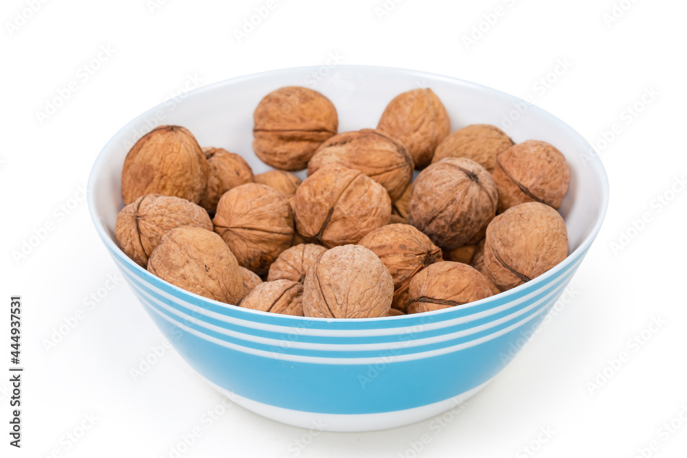 Unshelled walnuts in blue bowl, close-up in selective focus Unshelled walnuts in blue bowl, close-up in selective focus
