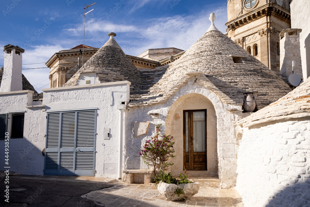 Beautiful town of Alberobello with typical trulli houses built from stone among green plants and flowers, main touristic district, Apulia region UNESCO World Heritage Site 