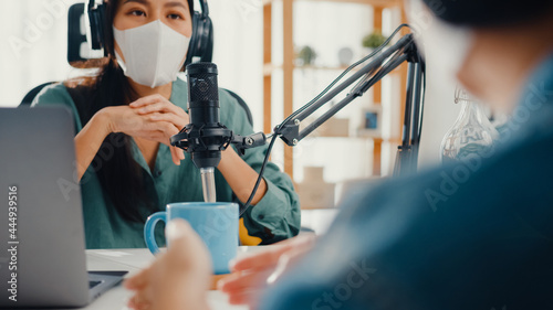 Asia girl radio host record podcast use microphone wear headphone interview guest content wear mask protect virus conversation talk and listen in her room. Podcast from home, coronavirus quarantine.