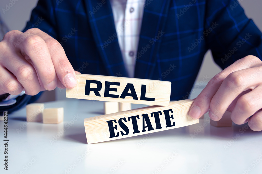 Obraz premium Real estate text from wooden blocks on desk