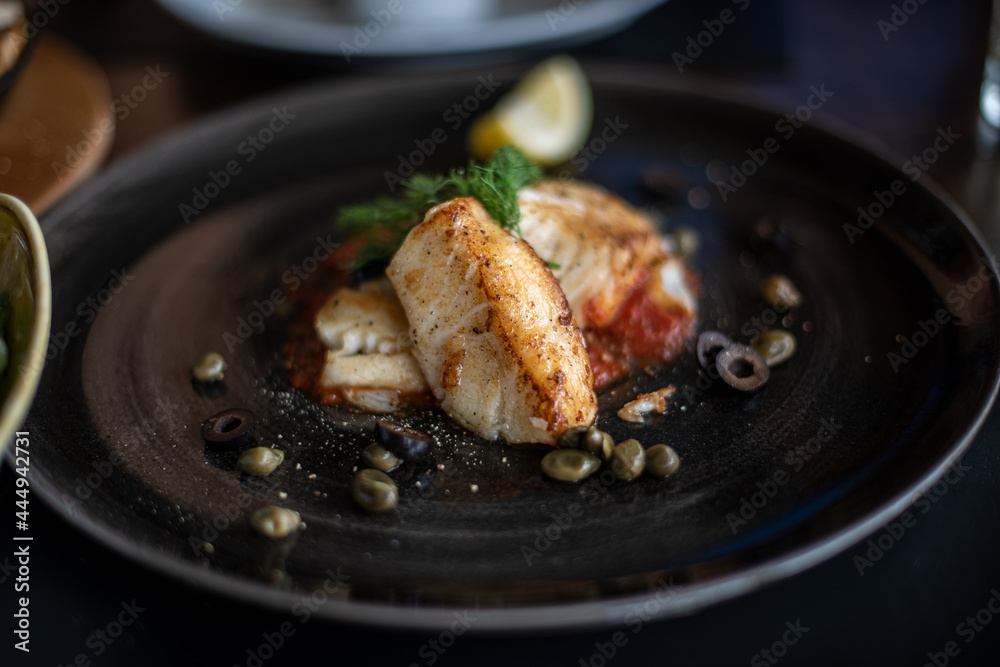 Grilled sea bass with lime served on black plate. Grilled sea bass with lime served on black plate.