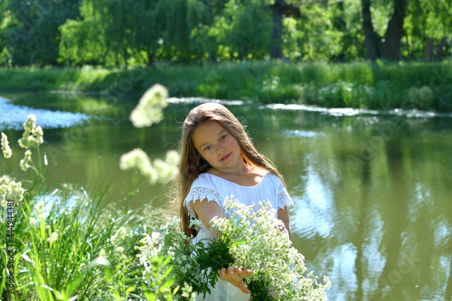 Girl in beautiful wreath on summer meadow near the river. Feast of Ivan Kupala.Midsummer. Earth Day.Pagan holiday of Ivan Kupala