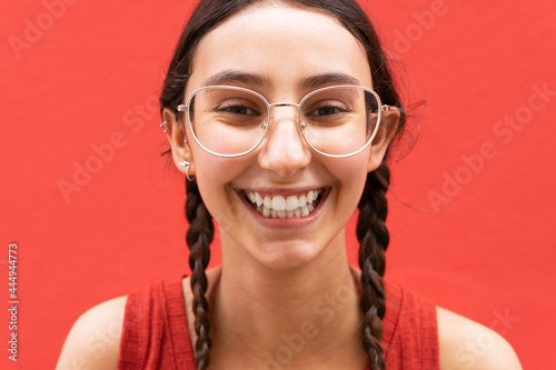 Happy woman with pigtails on red background in city photo