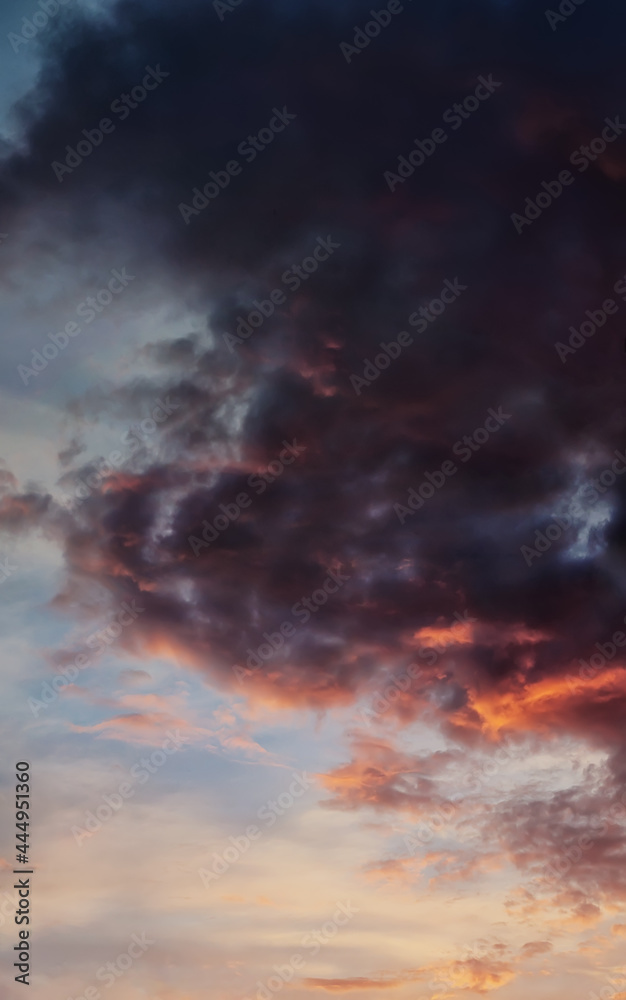 Dramatic sky with dark clouds illuminated with evening sun, vertical panorama.