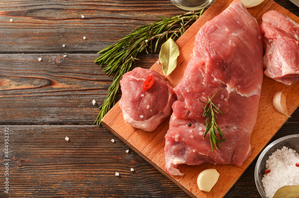  pork tenderloin with rosemary on a cutting board on a dark wooden background