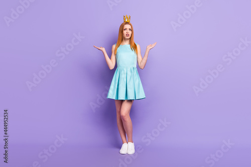 Full size photo of young clueless unhappy woman shrug shoulders wear crown isolated on purple color background
