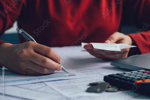 Close up woman using a pen filling form of Individual Income Tax Return, in living room at home.Expenses, account, taxes, home budget concept