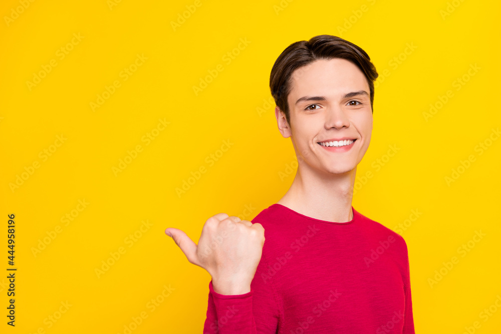 Photo of pretty charming young gentleman wear red sweater pointing thumb up empty space smiling isolated yellow color background Photo of pretty charming young gentleman wear red sweater pointing thumb up empty space smiling isolated yellow color background