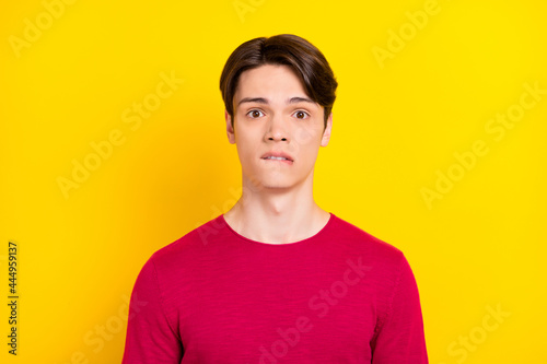 Photo of scared brunet young guy wear red sweater isolated on yellow color background © deagreez