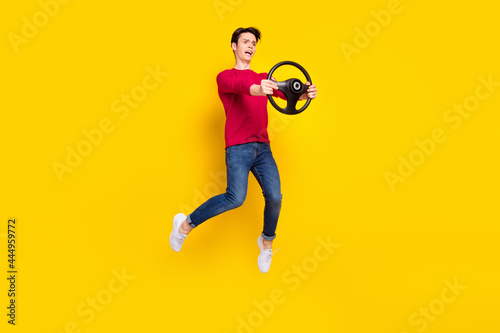 Full body photo of angry brunet millennial guy jump hold wheel wear red sweater jeans isolated on yellow background © deagreez