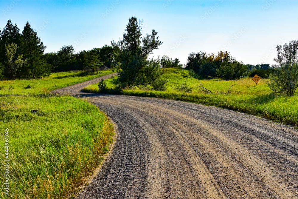 Naklejka premium Gravel roads will take you on a relaxing journey away from the congestion into the wide open spaces such as this one in North Dakota.