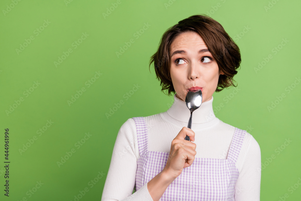 Photo of young girl lick spoon dream look empty space food eat hunger diet isolated over green color background Photo of young girl lick spoon dream look empty space food eat hunger diet isolated over green color background