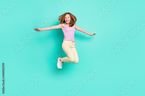 Full length photo of lovely brown teen girl jump wear top pants isolated on teal color background