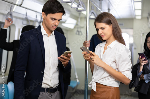 man and woman passenger using smartphone in the subway train