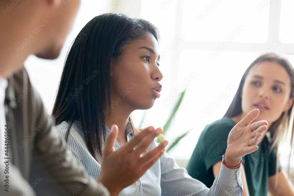 Serious mixed race Black student girl, intern speaking at learning seminar, conference lecture, asking question to teacher or coworkers. Employee, manager speaking at meeting, presenting solution - obrazy, fototapety, plakaty 