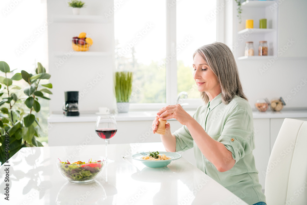 Profile side view portrait of attractive dreamy grey-haired woman eating yummy tasty dinner alone at home light white indoors Profile side view portrait of attractive dreamy grey-haired woman eating yummy tasty dinner alone at home light white indoors