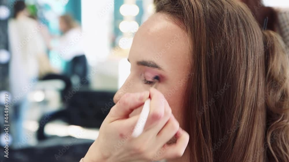 A hand with a brush applies shadow on the eyelid, a girl in a beauty salon. Makeup artist makes makeup to a young woman. Beautician, business concept. Beauty salon, skin care. UHD 4K. A hand with a brush applies shadow on the eyelid, a girl in a beauty salon. Makeup artist makes makeup to a young woman. Beautician, business concept. Beauty salon, skin care. UHD 4K.