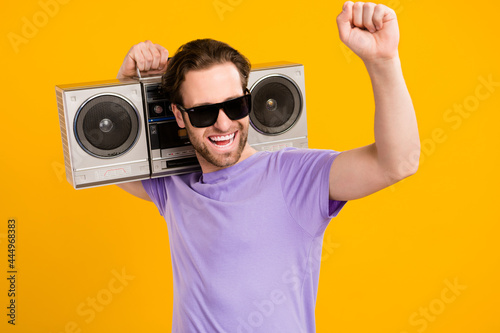 Photo of carefree cool guy hold boombox have party fun wear violet t-shirt isolated yellow color background