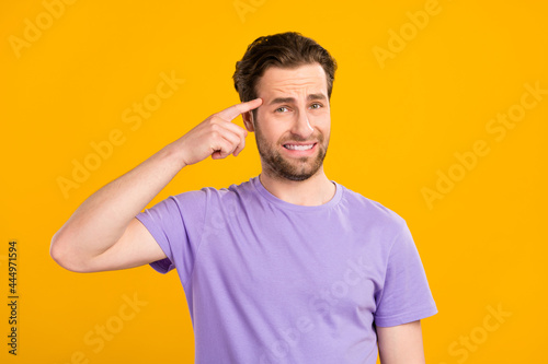 Photo of unhappy pretty young guy dressed purple t-shirt finger forehead isolated yellow color background