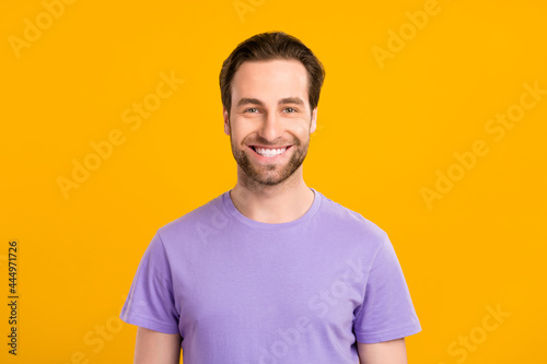 Photo of positive handsome guy look camera toothy beaming smile wear purple t-shirt isolated yellow color background