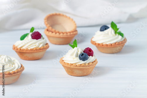 Canvastavla Mini tartlets with whipped cream and fresh berries, on a white table, blurred fo