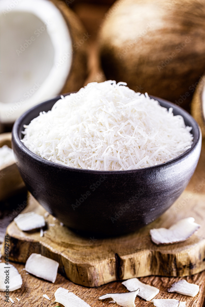 grated coconut inside a clay bowl, with coconut and coconut pieces in the background, culinary ingredient for sweets grated coconut inside a clay bowl, with coconut and coconut pieces in the background, culinary ingredient for sweets