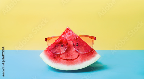 Summer times of a funny attractive watermelon in stylish red sunglasses on a blue and yellow background. the concept of a minimal idea. food and drinks that are usually enjoyed at summer festivals