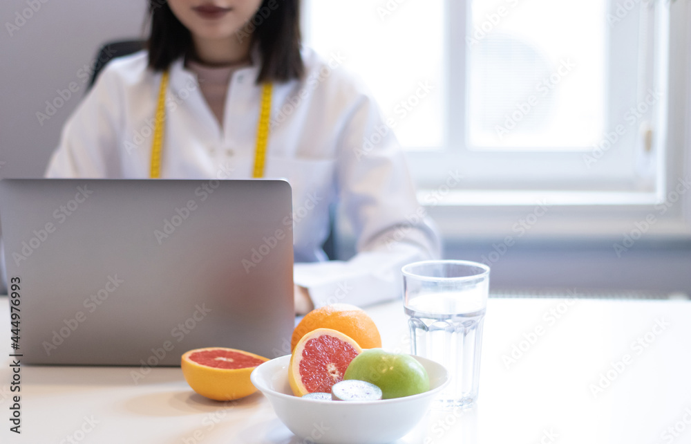 dietitian woman working with her computer and an office with mixed fruit and water on the table dietitian woman working with her computer and an office with mixed fruit and water on the table