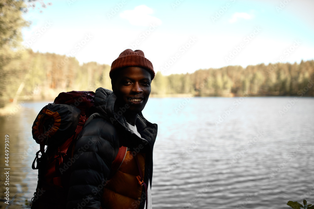 Calming lake in mountains surrounded with trees, virgin nature. Peaceful spot for meditation, camping, lost in thoughts. Afro american guy enjoy travelling alone. Adventure time concept. Copy space Calming lake in mountains surrounded with trees, virgin nature. Peaceful spot for meditation, camping, lost in thoughts. Afro american guy enjoy travelling alone. Adventure time concept. Copy space