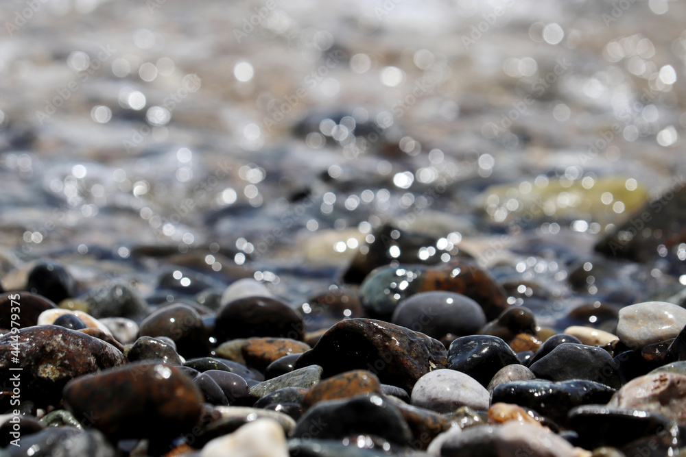 Wet pebble stones on blurred background of sea waves. Summer vacation concept Wet pebble stones on blurred background of sea waves. Summer vacation concept