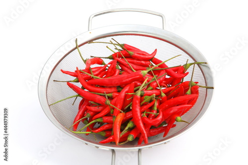 Group of fresh red hot chilli peppers in metal basket on white background