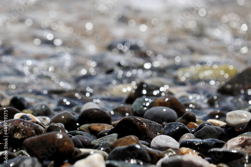 Fototapeta Naklejka Na Ścianę i Meble -  Wet pebble stones on blurred background of sea waves. Summer vacation concept