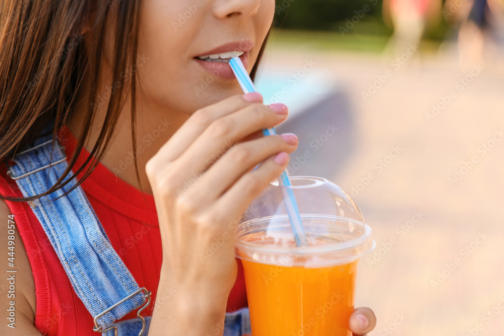 Young woman drinking tasty juice outdoors, closeup