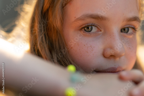 A young cute girl with freckles is looking straight to the camera
