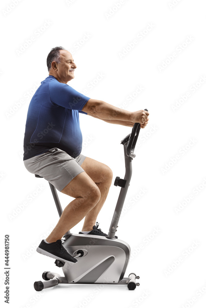 Full length profile shot of a corpulent mature man riding a stationary bike Full length profile shot of a corpulent mature man riding a stationary bike