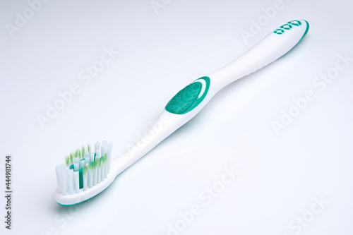 white-green toothbrush on a white background. Oral health. Personal hygiene.