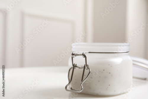 Jar of natural salt scrub on white table. Space for text