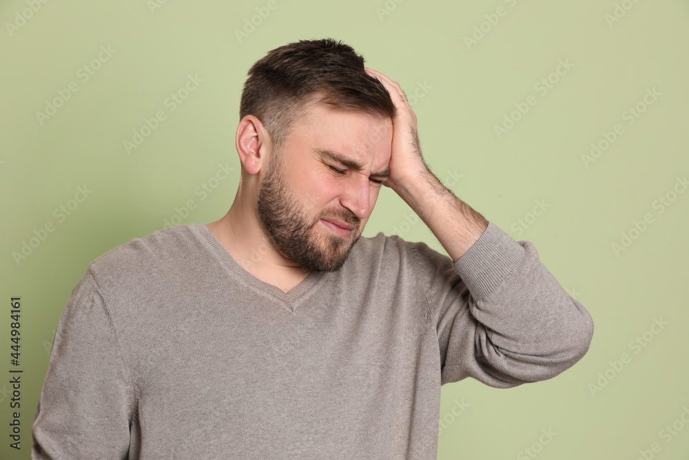 Man suffering from migraine on light green background Man suffering from migraine on light green background