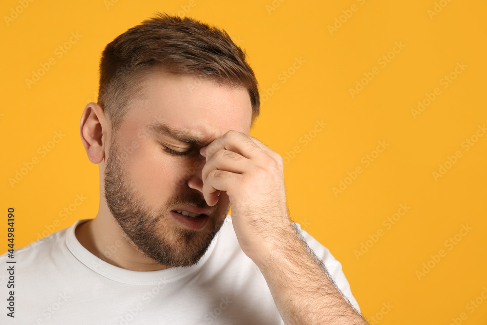 Fototapeta premium Man suffering from migraine on yellow background, space for text