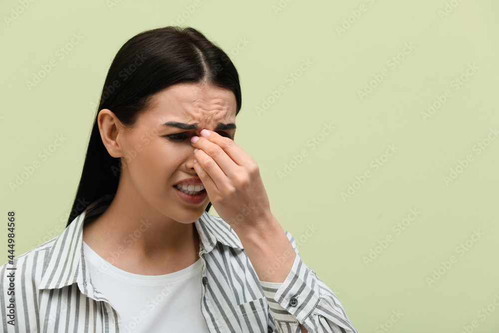 Woman suffering from migraine on light green background, space for text Woman suffering from migraine on light green background, space for text