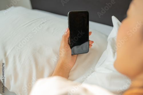 Asian woman with attractive smile use tablet smartphone on white bed, Portrait young beauty relax in bedroom. Technology people connection digital online marketing e-commerce concept
