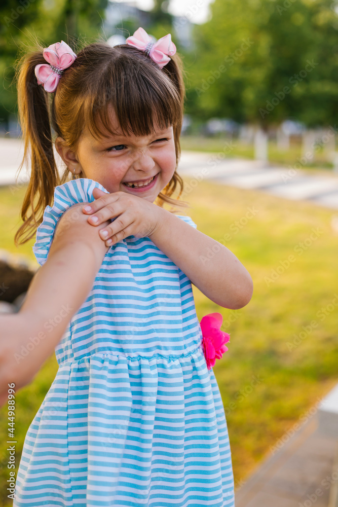 A little girl walks in the park in the summer. The child is bitten by mosquitoes. A little girl walks in the park in the summer. The child is bitten by mosquitoes.