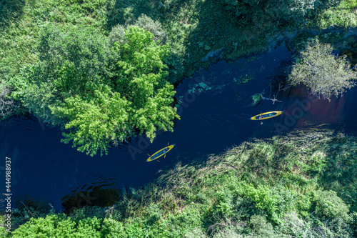 Fototapeta Naklejka Na Ścianę i Meble -  Canoes on the calm river. Aerial top view. Beautiful picture of river and green banks of the river in the summer morning day.