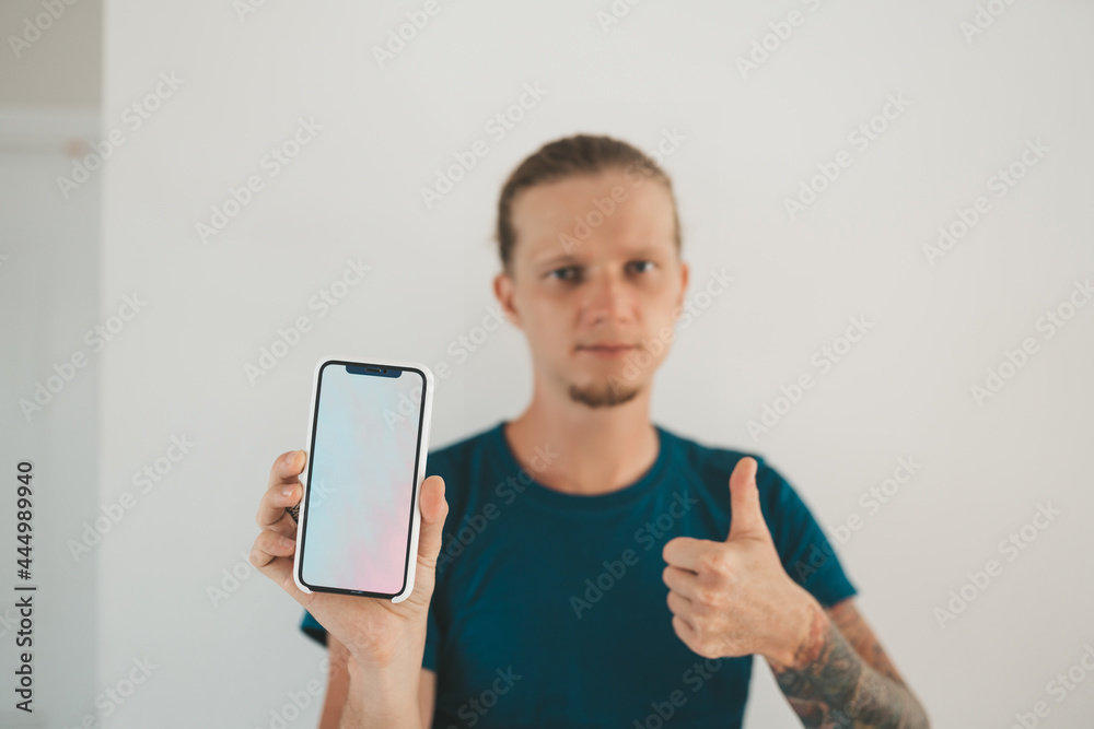 Man in blue shirt standing at a wall and chatting in his phone