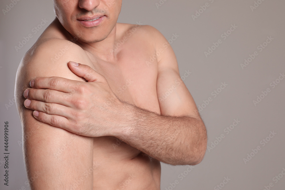 Naklejka premium Man suffering from shoulder pain on beige background, closeup