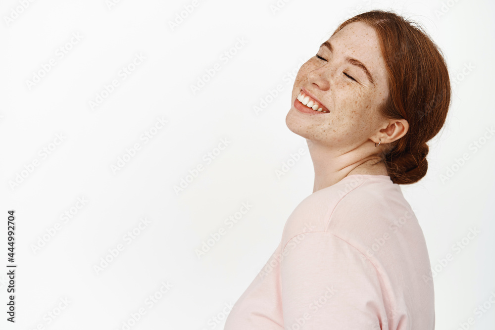 Close up portrait of redhead happy woman face, close eyes and smiling carefree, beauty is in happiness, daydreaming about something positive, pleasant memories, white background Close up portrait of redhead happy woman face, close eyes and smiling carefree, beauty is in happiness, daydreaming about something positive, pleasant memories, white background