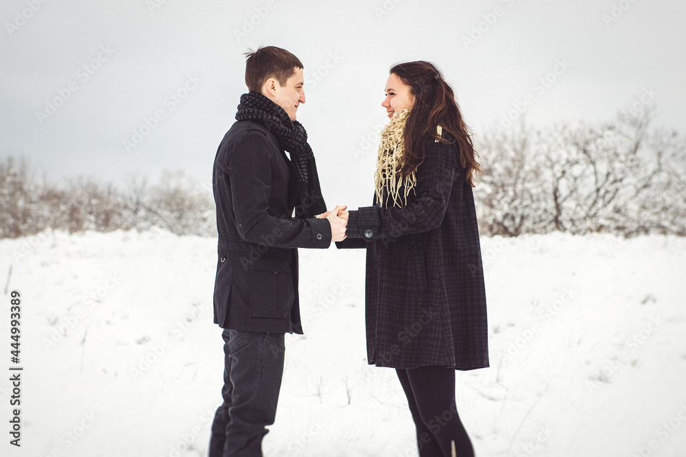 A guy and a girl in warm clothes and scarves on a walk in the snowy weather