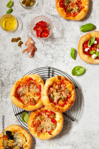 Mini pizzas - pizzette - topped with cheese and tomato plus Italian ham and chilli photo